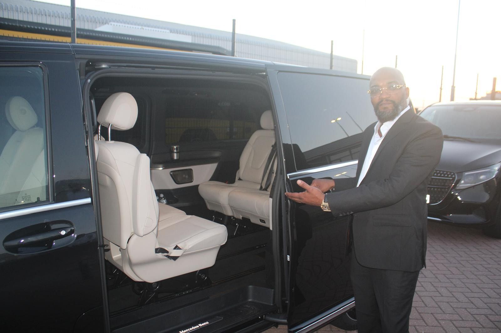 Chauffeur presenting the open V-Class door, cream leather cabin